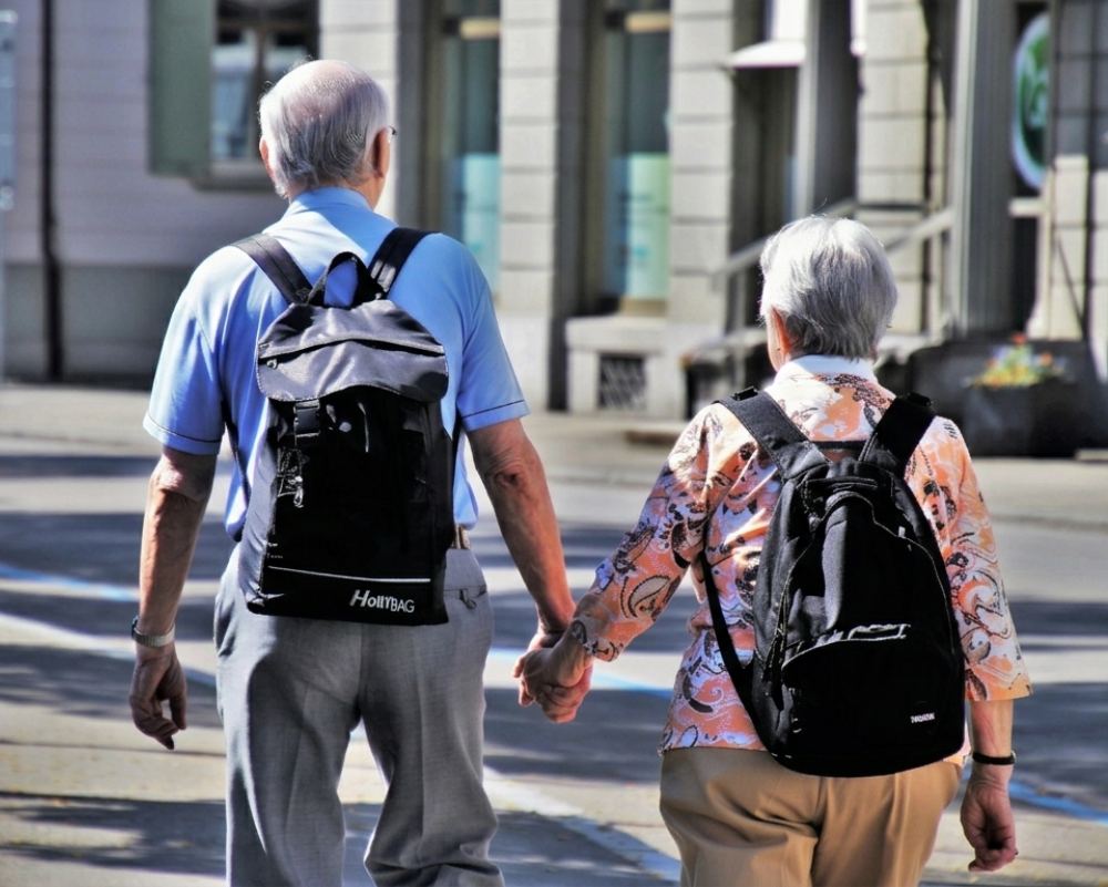 Coppia anziana che cammina mano nella mano, simbolo di pensione, terza età e pianificazione per vivere di rendita.