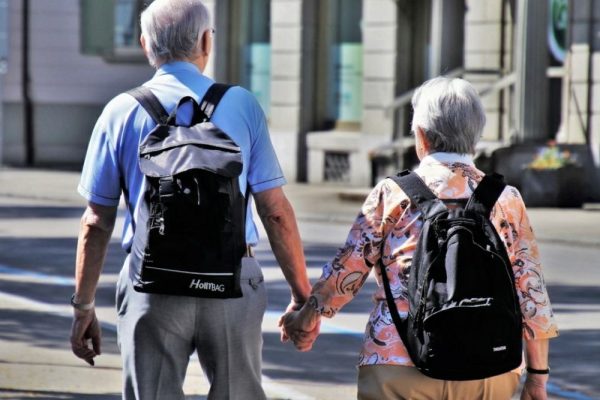 Coppia anziana che cammina mano nella mano, simbolo di pensione, terza età e pianificazione per vivere di rendita.