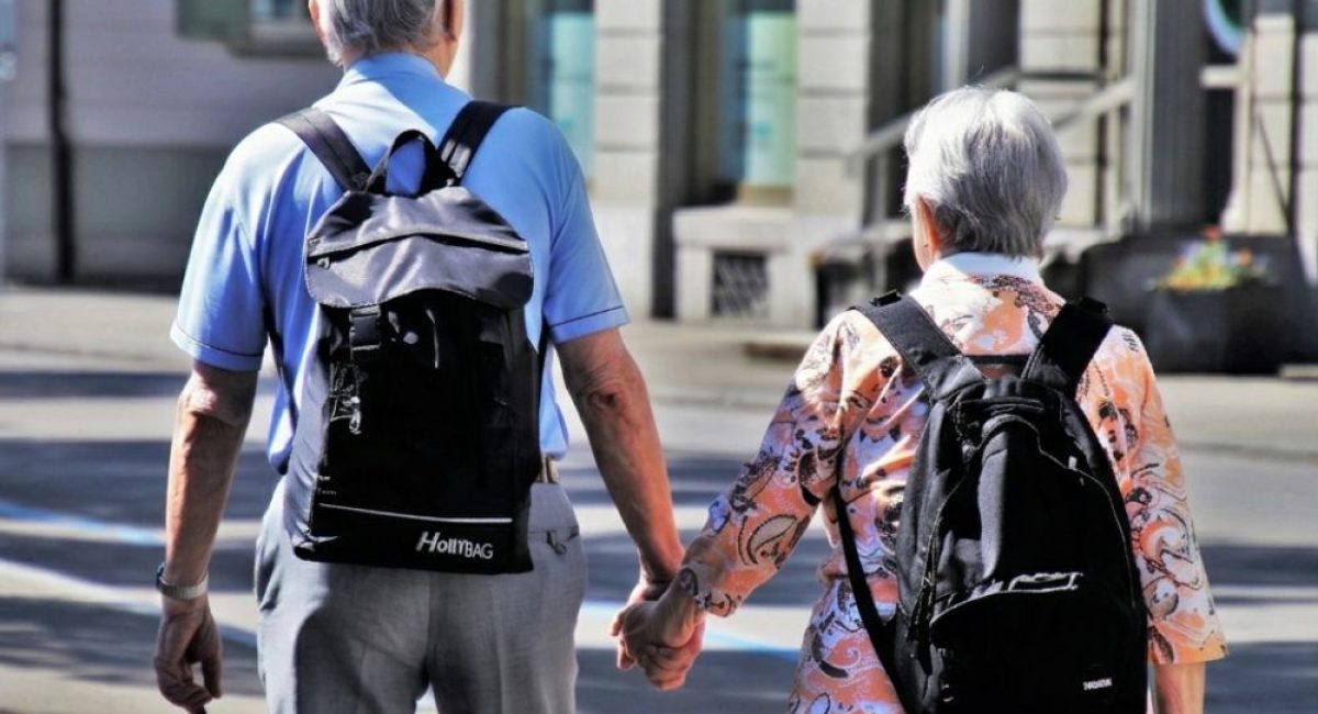 Coppia anziana che cammina mano nella mano, simbolo di pensione, terza età e pianificazione per vivere di rendita.